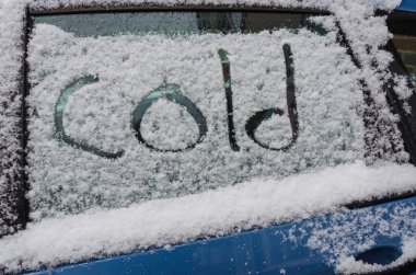 Soğuk kelimesi karla kaplı bir arabanın camına yazılmış..