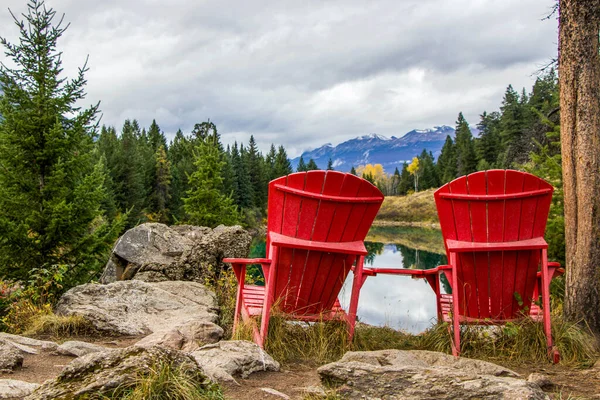 two red chairs beside a lake with mountain view