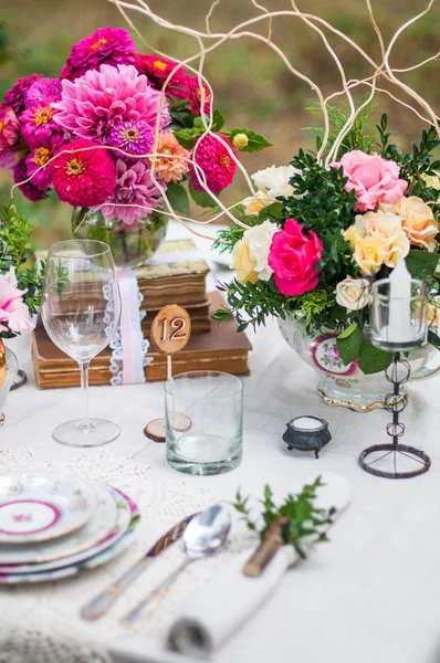 Μπουκέτο με λουλούδια και ένα τραπέζι καθόταν σε τα λευκά τραπεζομάντιλα — Φωτογραφία Αρχείου