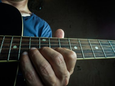 Portre fotoğraf bir adam tarafından oynanan bir akustik gitar.
