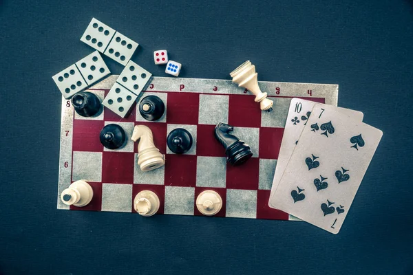 Various board games and figurines over checkers board — Stock Photo, Image