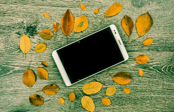 White modern tablet pc with blank empty screen on rustic vintage wood background with autumn leaves. — Stock Photo, Image