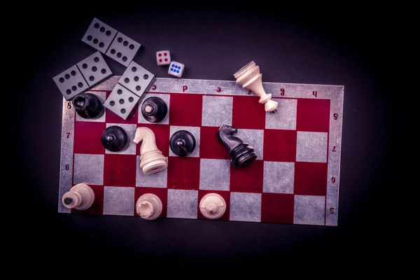 Various board games and figurines over checkers board — Stock Photo, Image