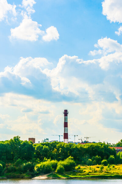 Industrial landscape with clouds and greenery.