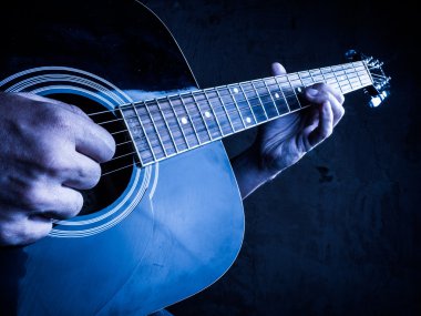Portre fotoğraf bir adam tarafından oynanan bir akustik gitar.