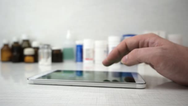 Mans main en utilisant un ordinateur tablette avec des médicaments médicaux en arrière-plan — Video