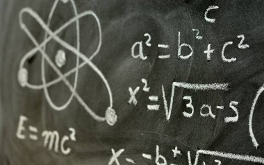 Tahtaya tebeşirle yazılmış fizik ve matematik işlemleri ve formülleri