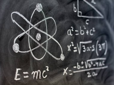 Tahtaya tebeşirle yazılmış fizik ve matematik işlemleri ve formülleri