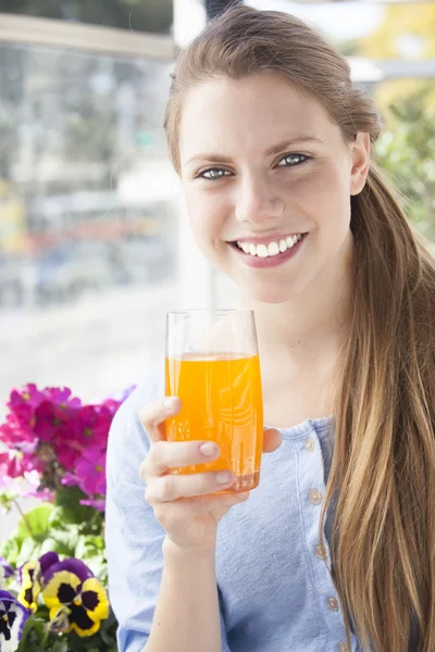 Mujer joven bebiendo jugo de naranja al aire libre — Foto de Stock