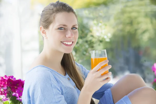 Mujer joven bebiendo jugo de naranja al aire libre — Foto de Stock