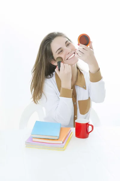 Cute brunette girl with coffe cup and color books in studio doing make up — Stock Photo, Image