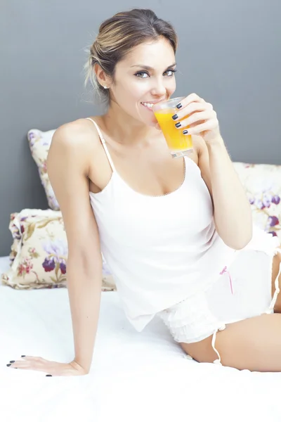 Relaxed woman drinking orange juice at home in bedroom — Stock Photo, Image