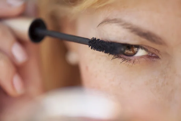 Retrato de una hermosa hembra poniéndose rímel en los ojos — Foto de Stock