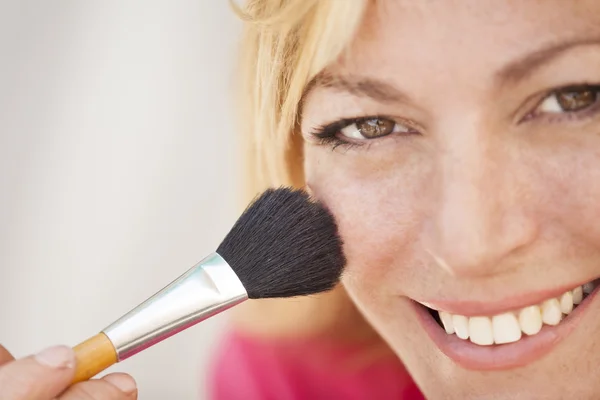 Beautiful young woman applying blush and smiling — Stock Photo, Image