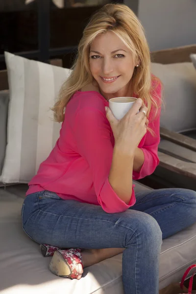 Femme souriante alors qu'elle tient une tasse dans ses mains — Photo