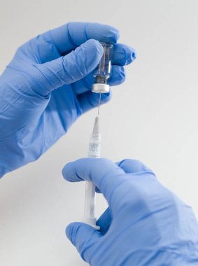 Mavi Plastik Eldivenler 'de Tıbbi Şırınga ve Beyaz Arkaplan' da Vial Kapanış