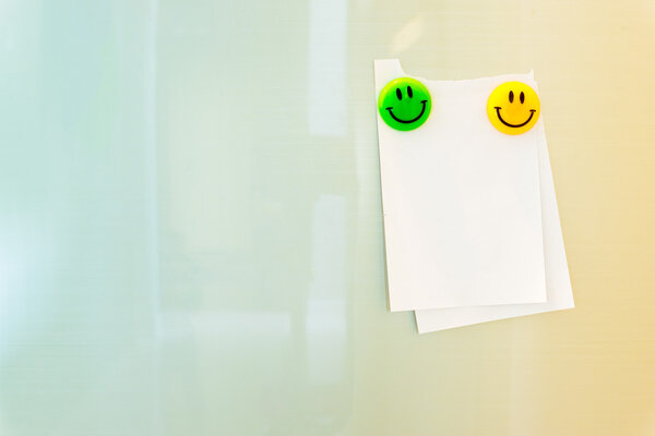 Notepad with smile magnets on pastel color tone background.