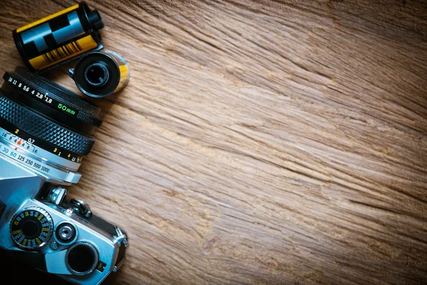 Top view of camera with film rolls on wooden floor.