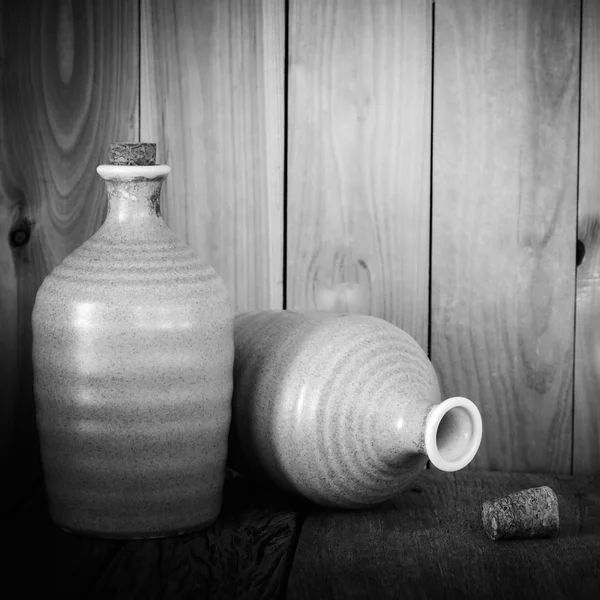 Ainda vida de garrafas de saquê com luz sobre fundo de madeira em blac — Fotografia de Stock