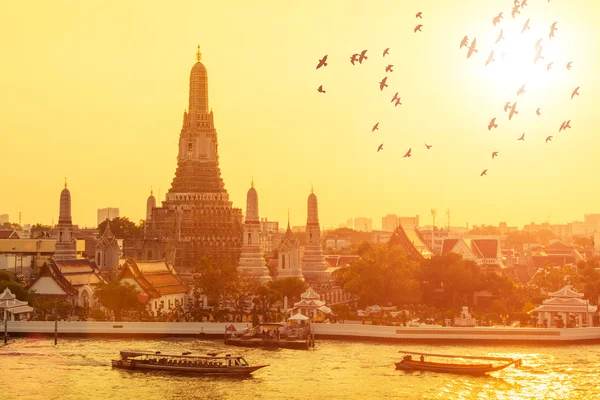 Wat arun med flygande fåglar i solnedgången på Bangkok, Thailand. — Stockfoto
