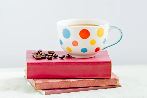 Taza de café con café tostado en los libros — Foto de Stock