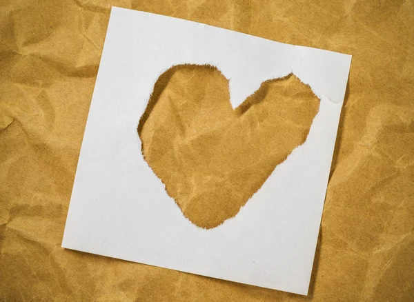 Forma de corazón en letras de revista recortadas puestas sobre papel marrón . — Foto de Stock