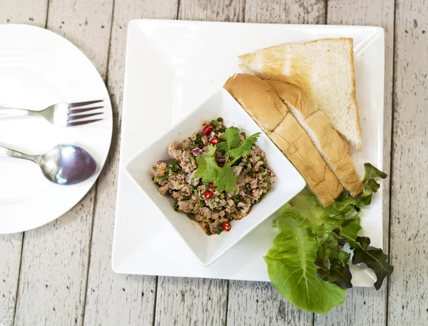 Spicy minced pork with bread on wooden table, Thai food — Stock Photo, Image