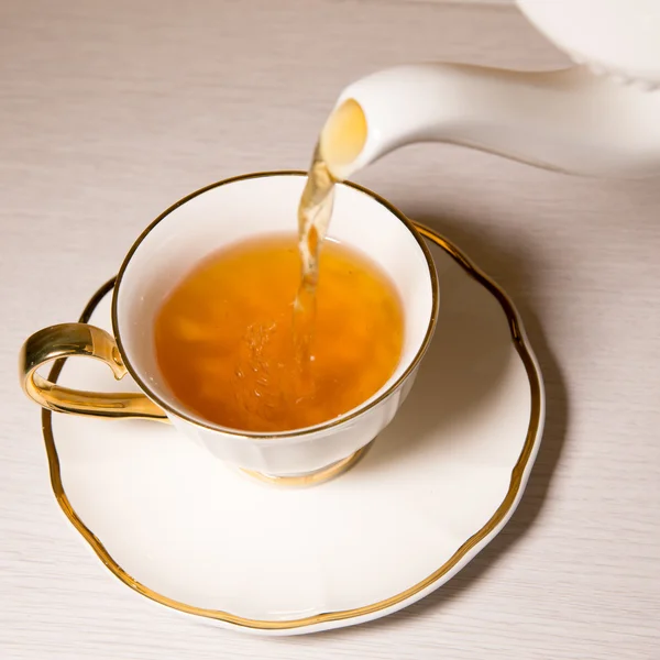Tè versato in tazza di tè, isolato su sfondo bianco . — Foto Stock