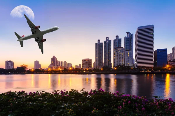 Modern building with flower, airplane and moon in the sky at twi