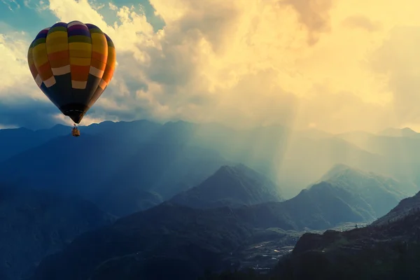 Dağ güneş ışını ile üzerinde uçan renkli sıcak hava balonu 
