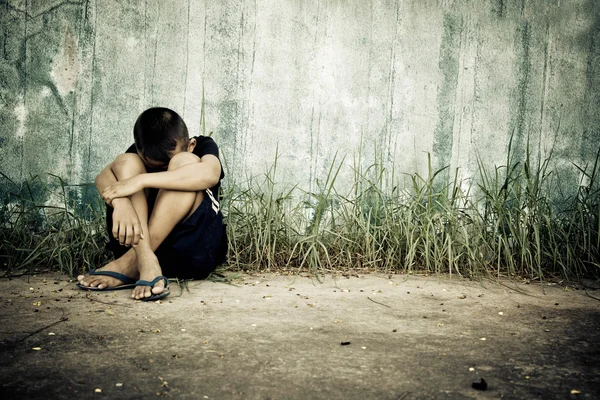 Duvar tarafından katta oturan üzgün çocuk 