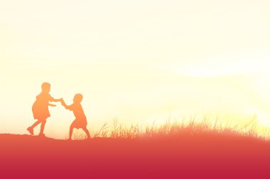 Siluet çocuklar gün batımında mutlu vakit geçiriyorlar. 