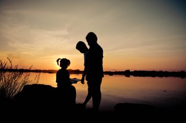 Siluet çocuklar gün batımında mutlu vakit geçiriyorlar. 