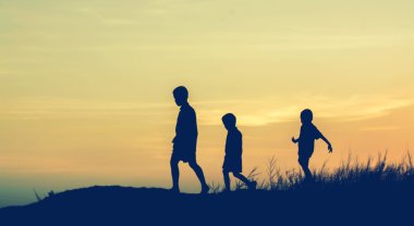 Siluet çocuklar gün batımında mutlu vakit geçiriyorlar. 