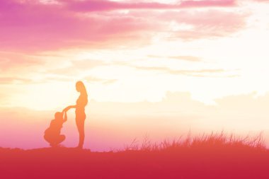 Mother encouraged her son outdoors at sunset, silhouette concept clipart