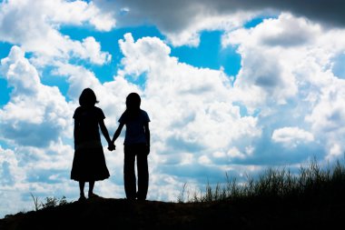 Birbirine bakan iki kızın silueti el ele tutuşuyor.