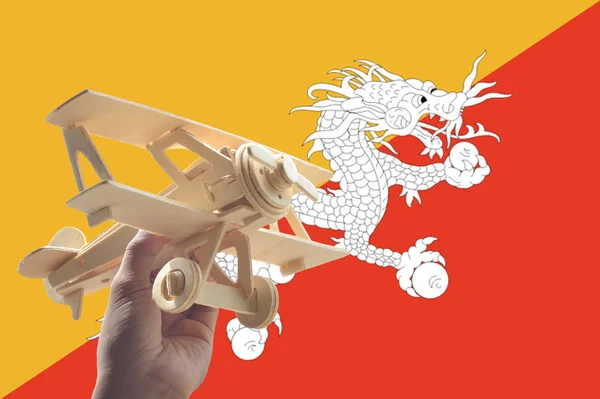 手拿着飞机飞机在不丹旗子 旅行概念 — 图库照片