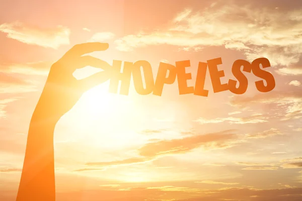 Silhouet van een hand met "Hopeloos" papier tekst — Stockfoto