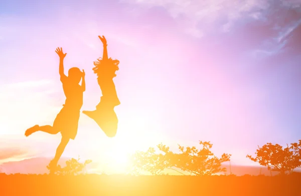 Menino com a menina saltando para o céu e tendo tempo feliz — Fotografia de Stock