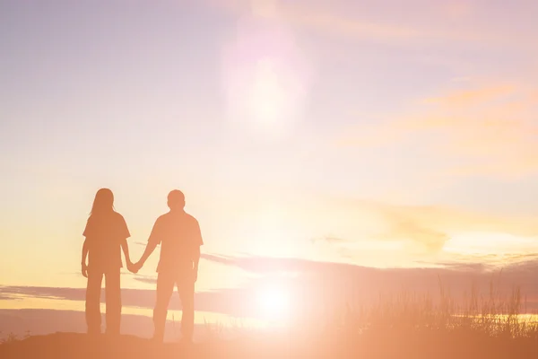 Силует жінки і чоловіка тримає руки на заході сонця — стокове фото