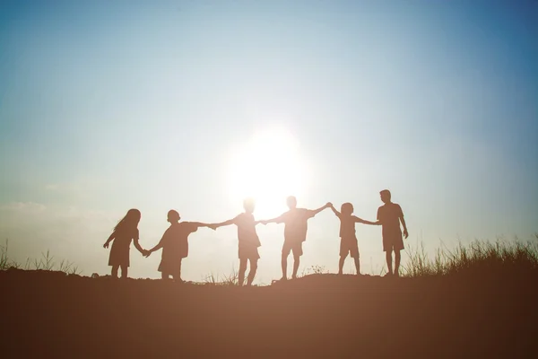 Silueta niños jugando en verano puesta del sol tiempo feliz — Foto de Stock