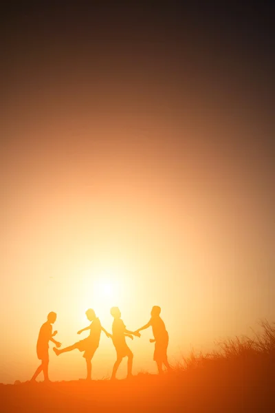 Silueta niños jugando en verano puesta del sol tiempo feliz — Foto de Stock