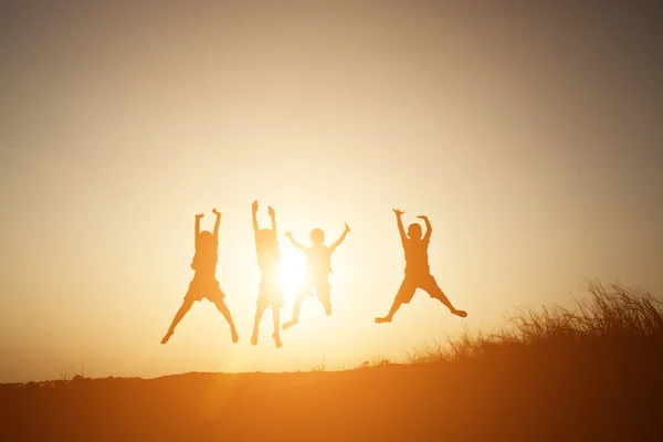 Silueta niños jugando en verano puesta del sol tiempo feliz — Foto de Stock