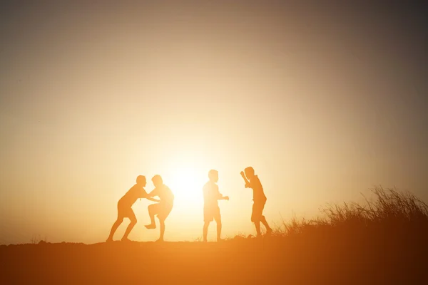 Silhouet kinderen spelen op zonsondergang gelukkig zomertijd — Stockfoto