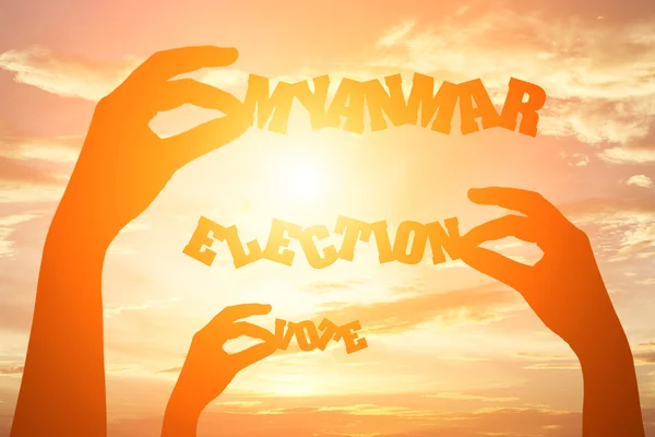 Silhouette of hand holding paper cut text "MYANMAR ELECTION VOTE — Stock Photo, Image