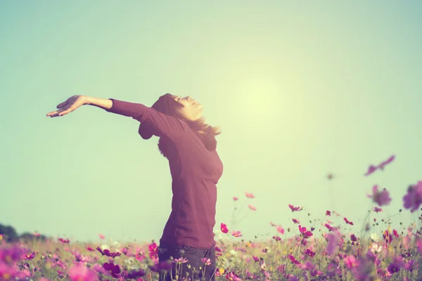 Щастя жінка залишається на відкритому повітрі в квітковому саду під сонячним світлом — стокове фото