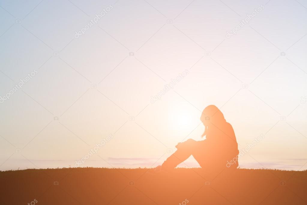 Sad woman silhouette sit alone in the grass so lonely