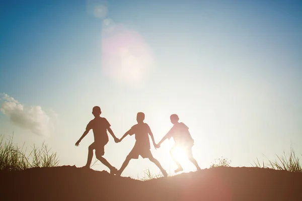 Silhouette dei bambini che giocano nel parco ora del tramonto — Foto Stock