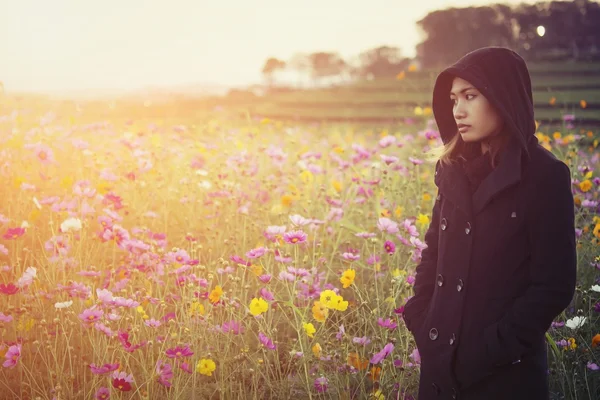 Mulheres bonitas vestindo casaco preto, de pé em um campo de flowe — Fotografia de Stock