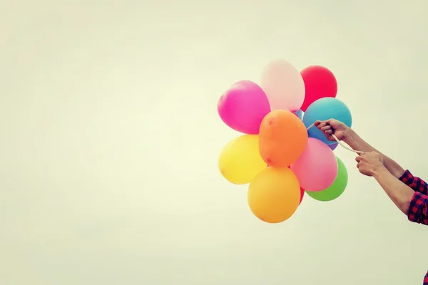 Hand of a teenage girl holding colorful balloons in the sunshine — Stock Photo, Image